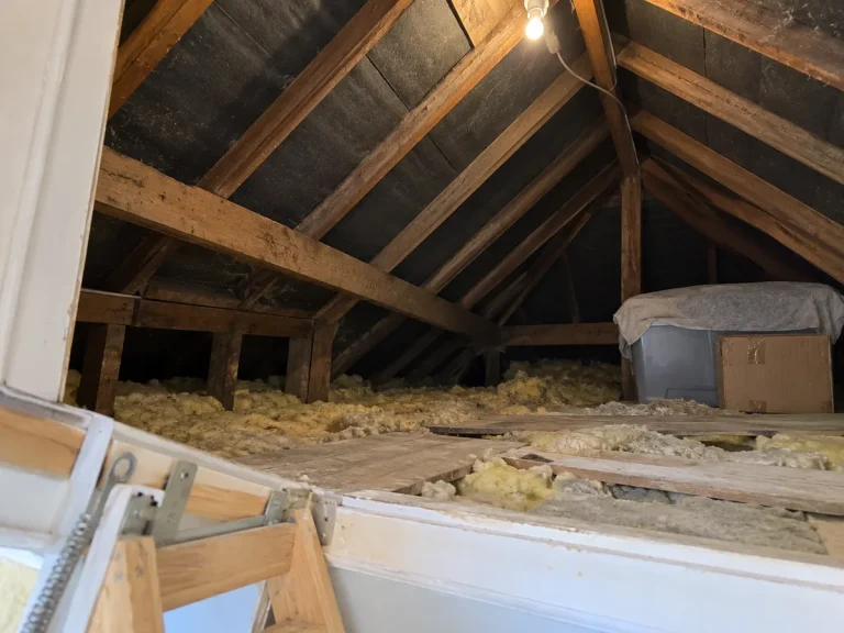 View through an open hatch into an empty, insulated house loft.